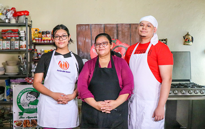 Sandra Flores en la cocina de su negocio con sus dos hijos